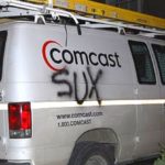 A dirty Comcast truck with sucks written on the back.