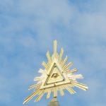 Gold pyramid Illuminati conspiracy symbol set against a blue sky.