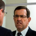 Angry white male lawyer staring at his self in the mirror.