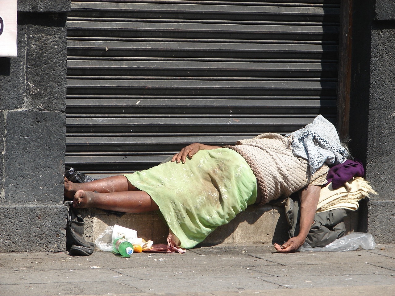 An elderly Mexican woman lying under a blanket in front of a wall in Mexico.