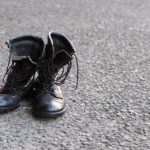 A pair of black Nazi military boots in the middle of the street alone.