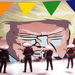 Male Mexican mariachi singers wearing sombreros and suits singing to painting of Donald Trump.
