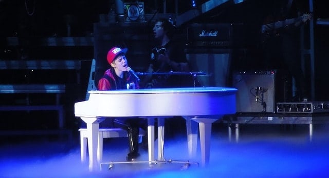 Pop musician Justin Beiber playing a piano in concert.
