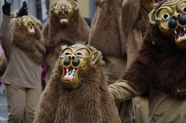 Group of men dressed in lion costumes walking down street.