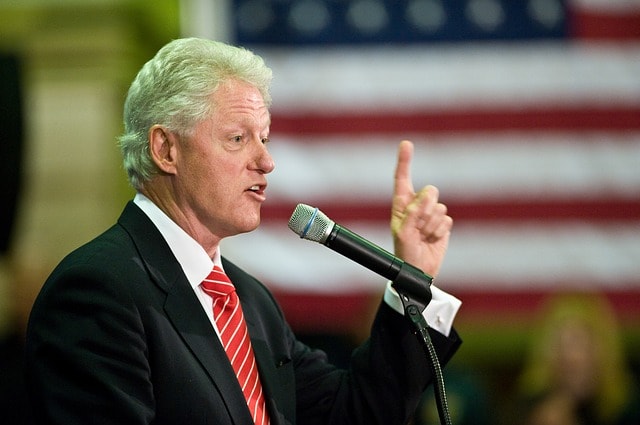 Former president Bill Clinton wearing a black suit talking into a microphone giving a speech.