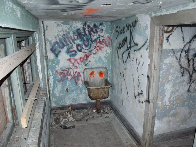 Dirty, disgusting bathroom with urine, feces, and graffiti everywhere.