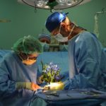Satire of two surgeons wearing blue scrubs performing a surgery on a plant in operating room.