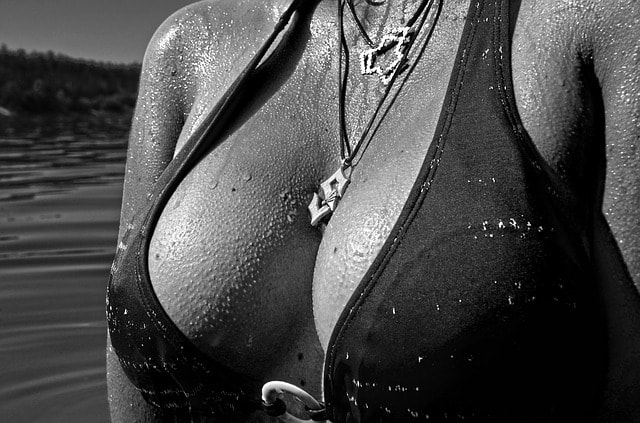 Closeup of large wet breasts on young white woman with a necklace between her cleavage.