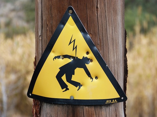 Tellow electric shock warning sign stapled to a telephone pole in Arizona.