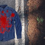 Denim shirt with blood on it lying on side of highway.
