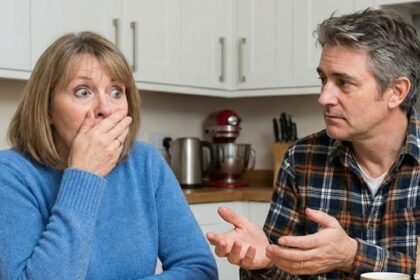 A mute white husband trying to communicate with his white wife at kitchen table.