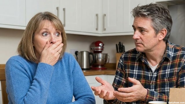 A mute white husband trying to communicate with his white wife at kitchen table.