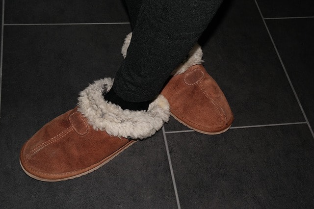 Closeup of woman wearing brown fuzzy Ugg slippers.