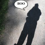 A large shadow of a man on a concrete sidewalk.