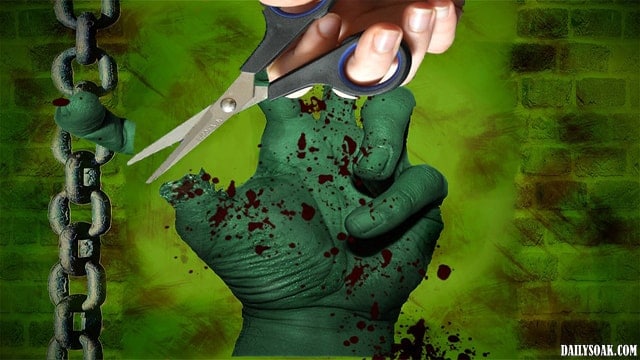 Man using scissors to cut off zombie's thumb.