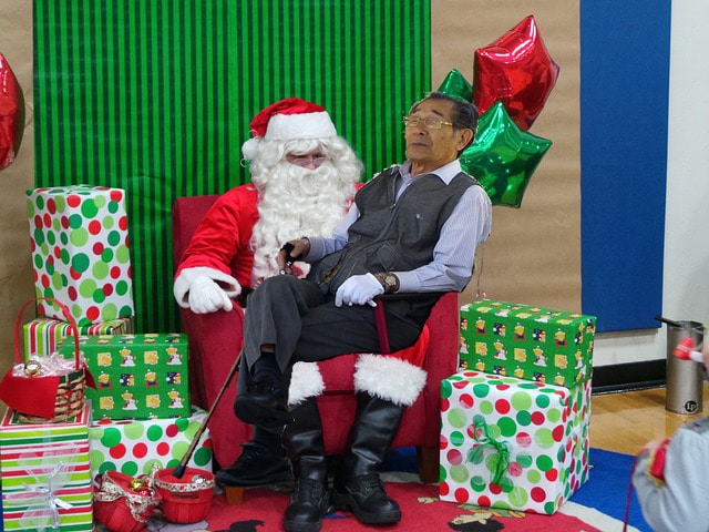 Elderly Japanese man sitting on Santa Claus' lap.