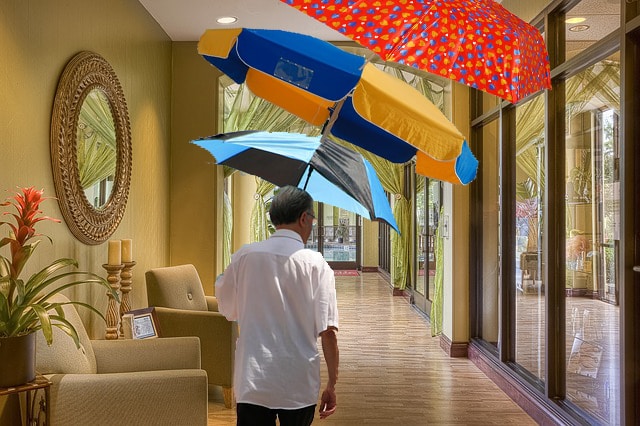 White man inside of his home holding three umbrellas.