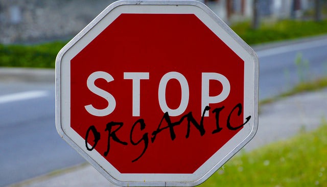 Stop sign with the word organic spray painted on it.