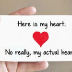 Man holding a Valentine's Day card in his hand with a big red heart on the card.