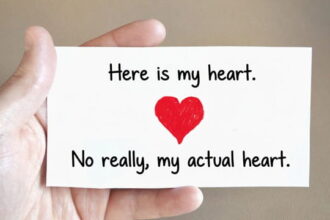 Man holding a Valentine's Day card in his hand with a big red heart on the card.