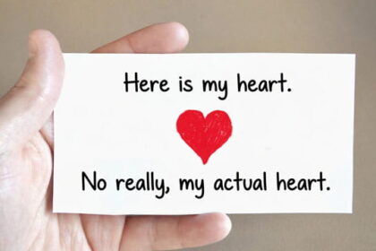 Man holding a Valentine's Day card in his hand with a big red heart on the card.