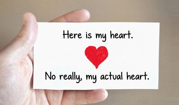 Man holding a Valentine's Day card in his hand with a big red heart on the card.