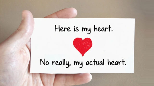 Man holding a Valentine's Day card in his hand with a big red heart on the card.