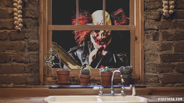 Killer clown staring in a house window.