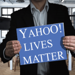 Man wearing black suit holding up sign that reads Yahoo Lives Matter.