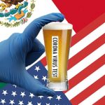 Hand in blue latex glove holding glass of beer in front of American and Mexican flag.