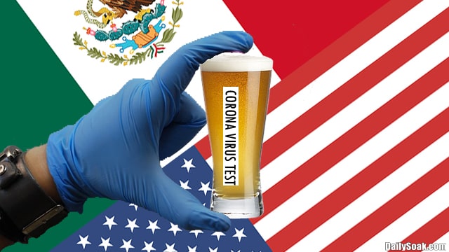 Hand in blue latex glove holding glass of beer in front of American and Mexican flag.