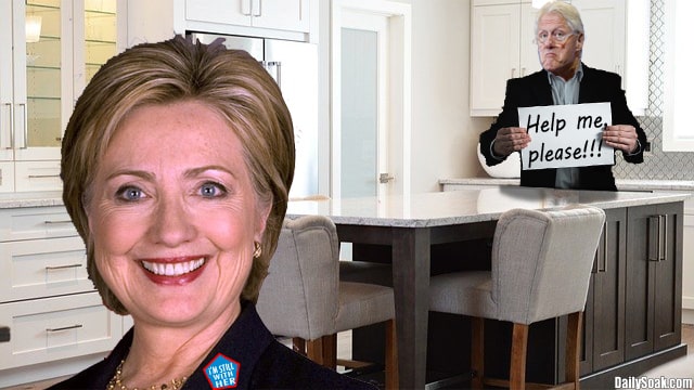 Bill Clinton in black suit and Hillary Clinton in black suit standing inside white kitchen.