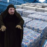 Jedi master in brown cloak standing in front of warehouse of water pallets.