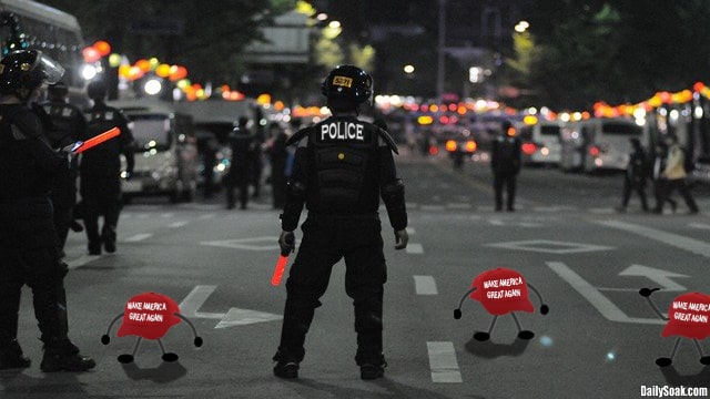 Three red hats on the ground at riot police feet.