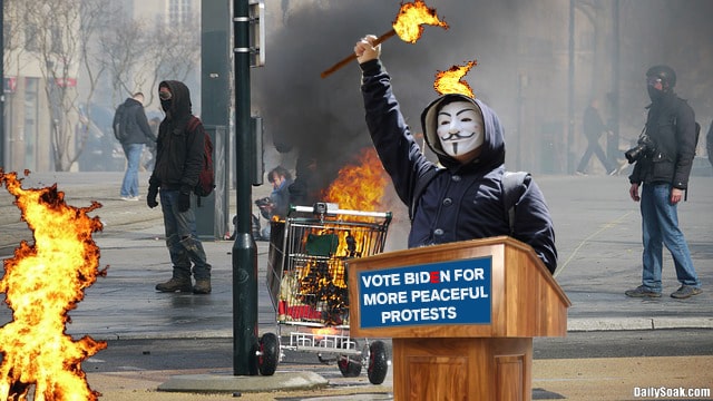 Rioters burning down a city during day.