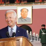 Joe Biden wearing blue suit in front of China flags and soldiers.