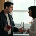 FBI agent wearing blue jacket screaming at scared woman inside kitchen.