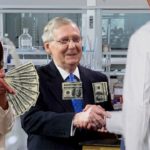 Congress members Nancy Pelosi and Mitch McConnell shaking hands with Big Pharma man in white lab coat inside vaccine laboratory.