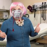Fat woman wearing blue shirt and face mask inside doctor's office.