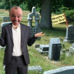 Phil Murphy wearing blue suit standing inside graveyard.