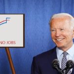 Joe Biden standing next to a chart of job creation numbers.