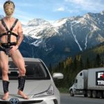 Justin Trudeau dressed in hockey mask standing on car near big rig truck.