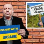 Joe Rogan wearing suit and holding sign with Ukraine flag.