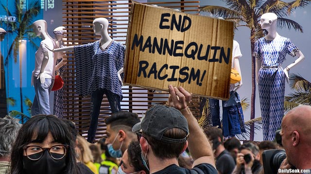 Numerous protesters outside store mannequin window.