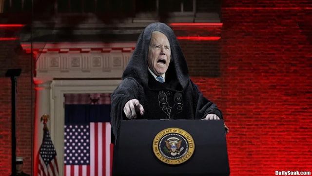 A robed Joe Biden giving a speech in front of red background.