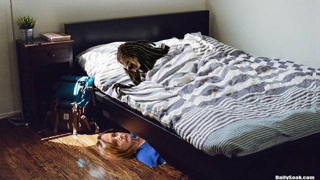Predator alien lying on bed while Nancy Pelosi hides under it.