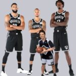 Kyrie Irving and NBA Brooklyn Nets players standing in team lineup.