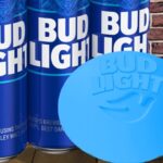 Bud light beers and a blue dove soap bar sitting on wooden table.