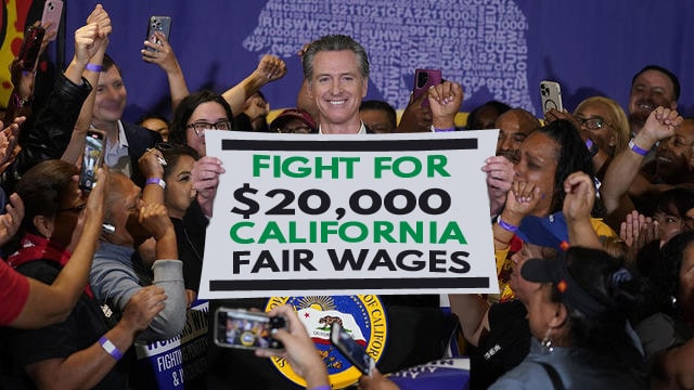 Gavin Newsom holding up sign in crowd after signing law to raise minimum wage.