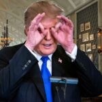 Donald Trump with his hands circled around his eyes while standing inside Mar-A-Lago.